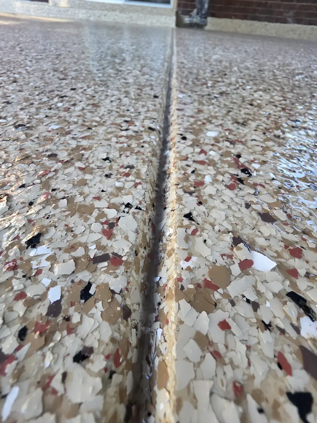 Close-up of a tan, red, and black flake epoxy floor at an expansion joint