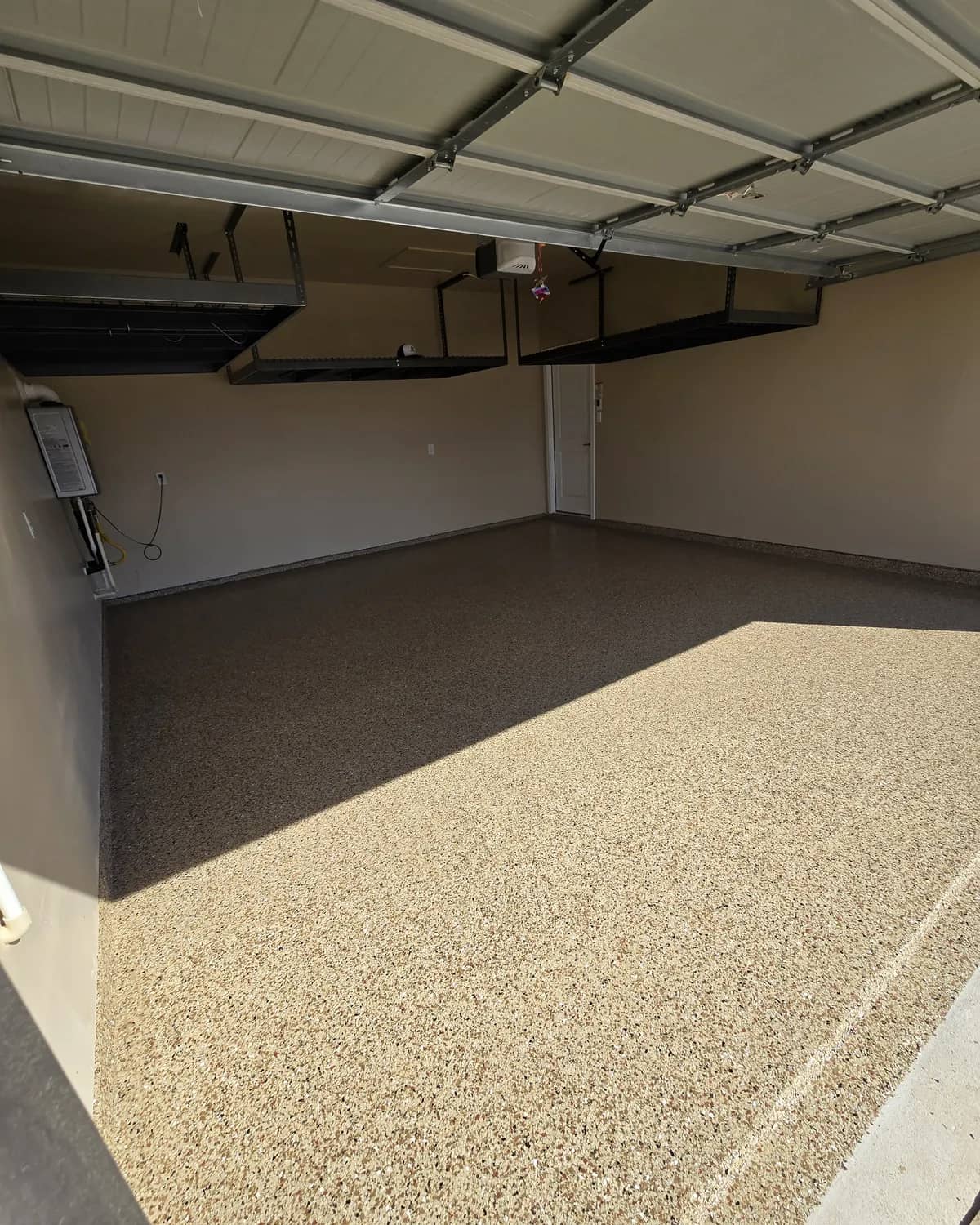 Finished garage with a tan flake epoxy floor and overhead storage racks