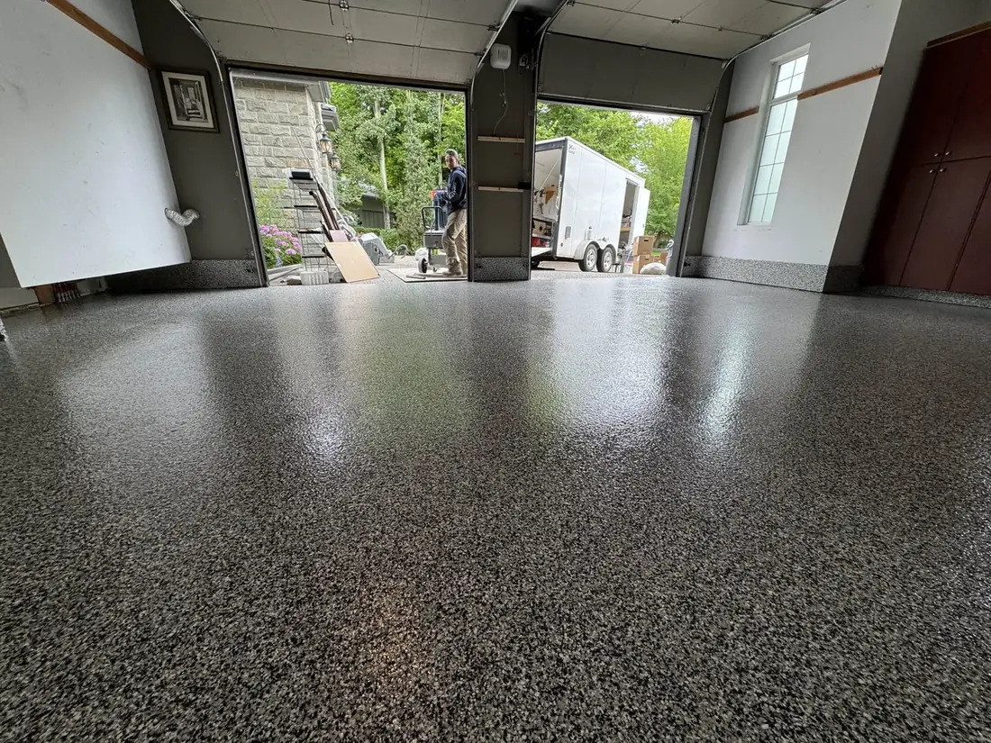 Two-bay garage finished with a glossy grey flake epoxy floor, doors open to the driveway