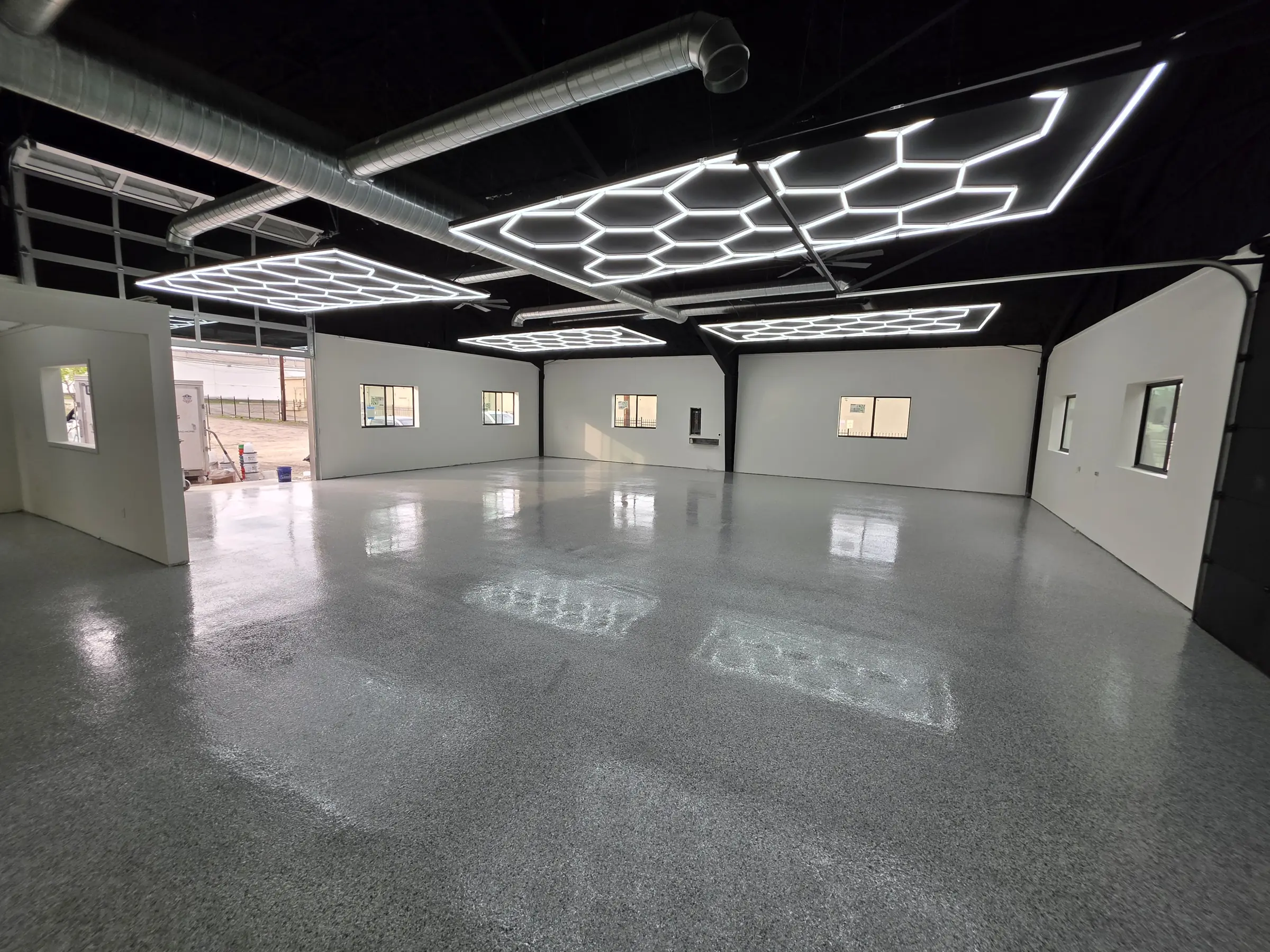 Shop interior with a gloss grey flake epoxy floor under hexagon LED lighting
