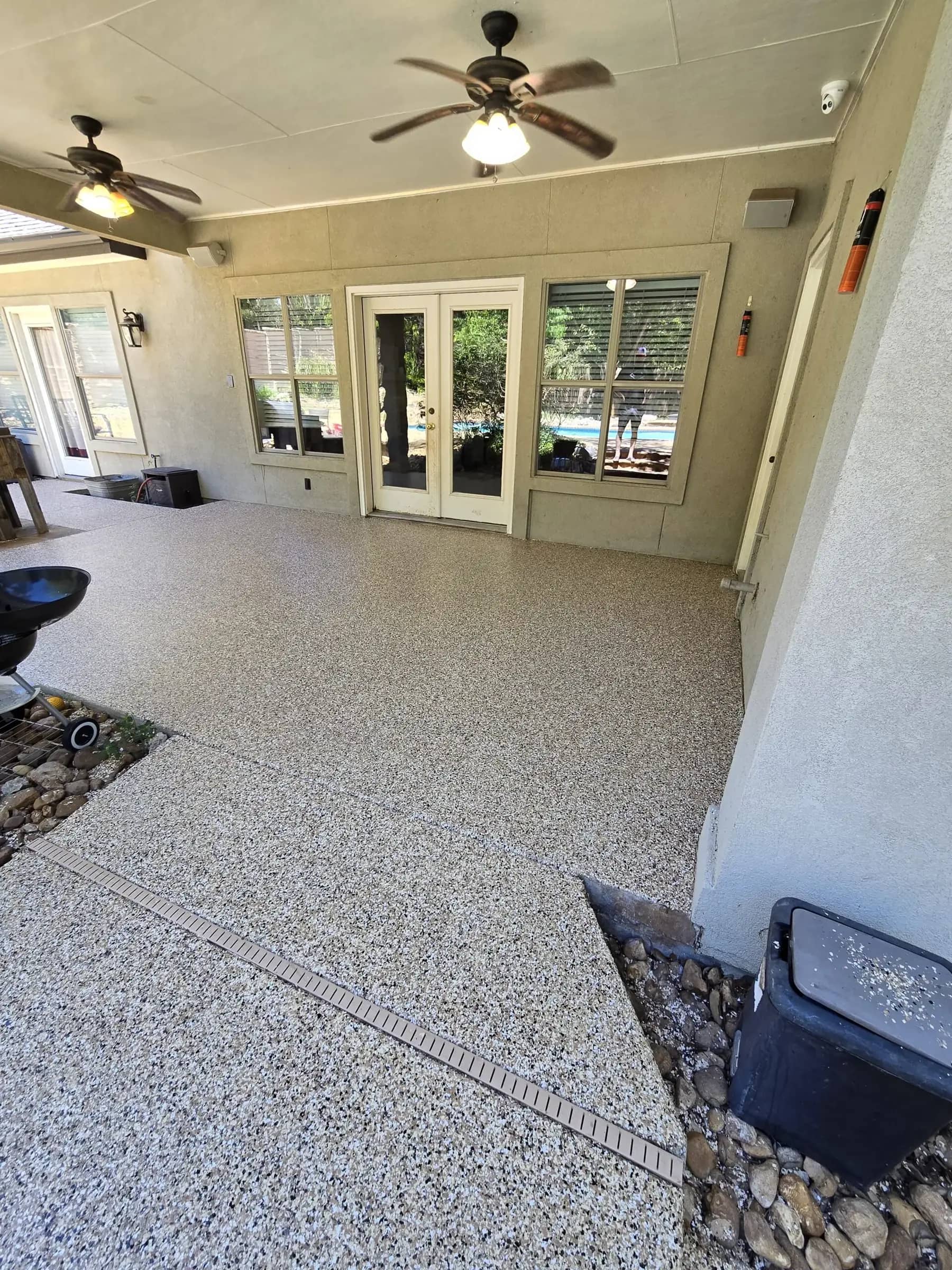 Covered back patio with a flake epoxy floor overlooking a pool