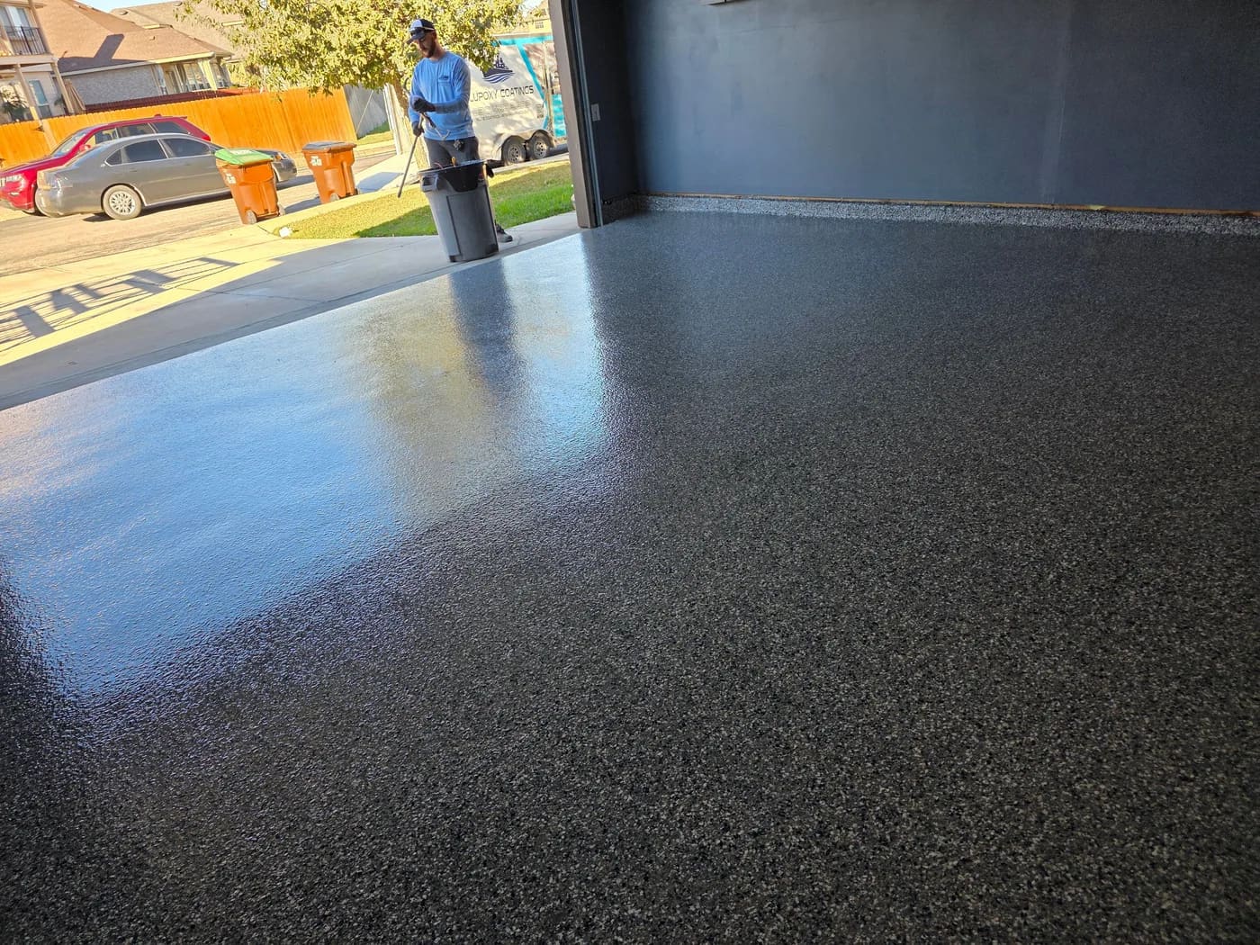 Blupoxy Coatings crew member with the company trailer outside a finished flake garage floor near Garden Ridge, TX